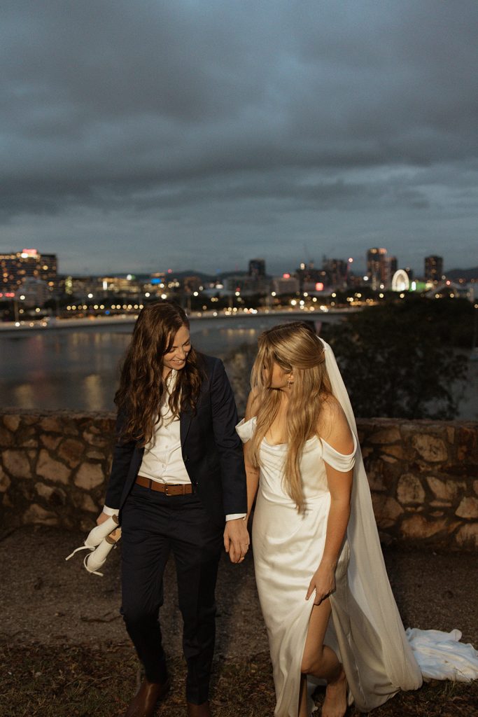 Brides walking along the river holding hands after their elopement in Brisbane