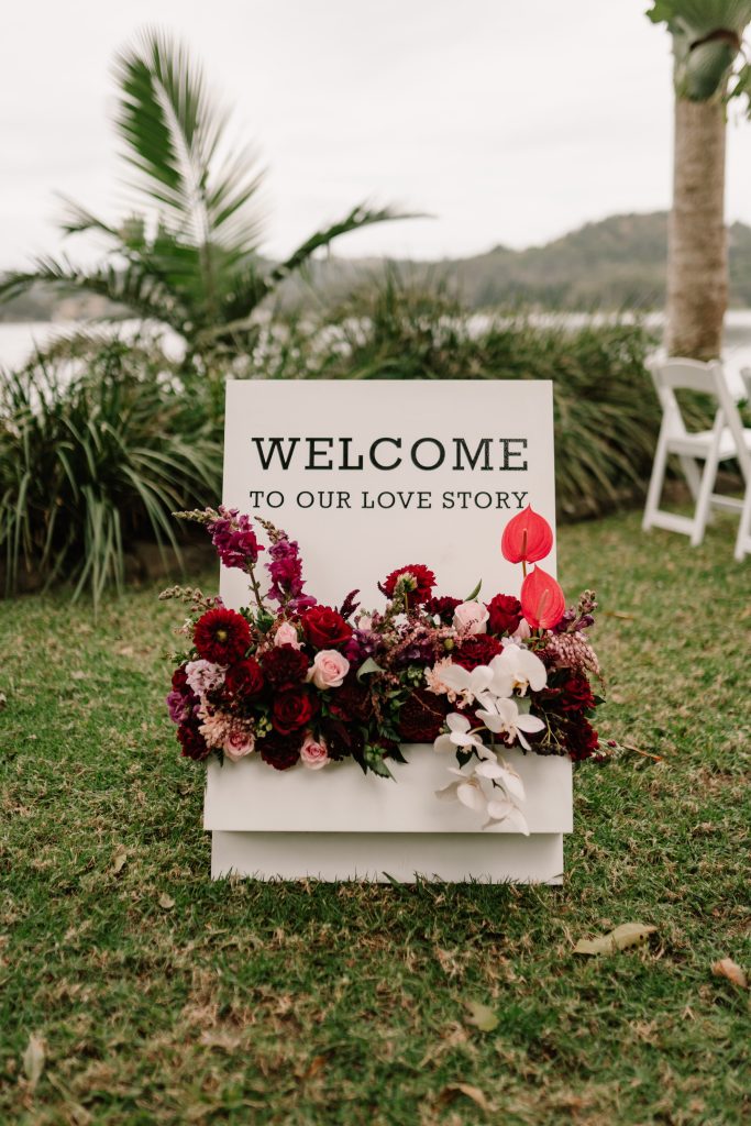 Welcome sign with deep red floral arrangement at Montville wedding venue