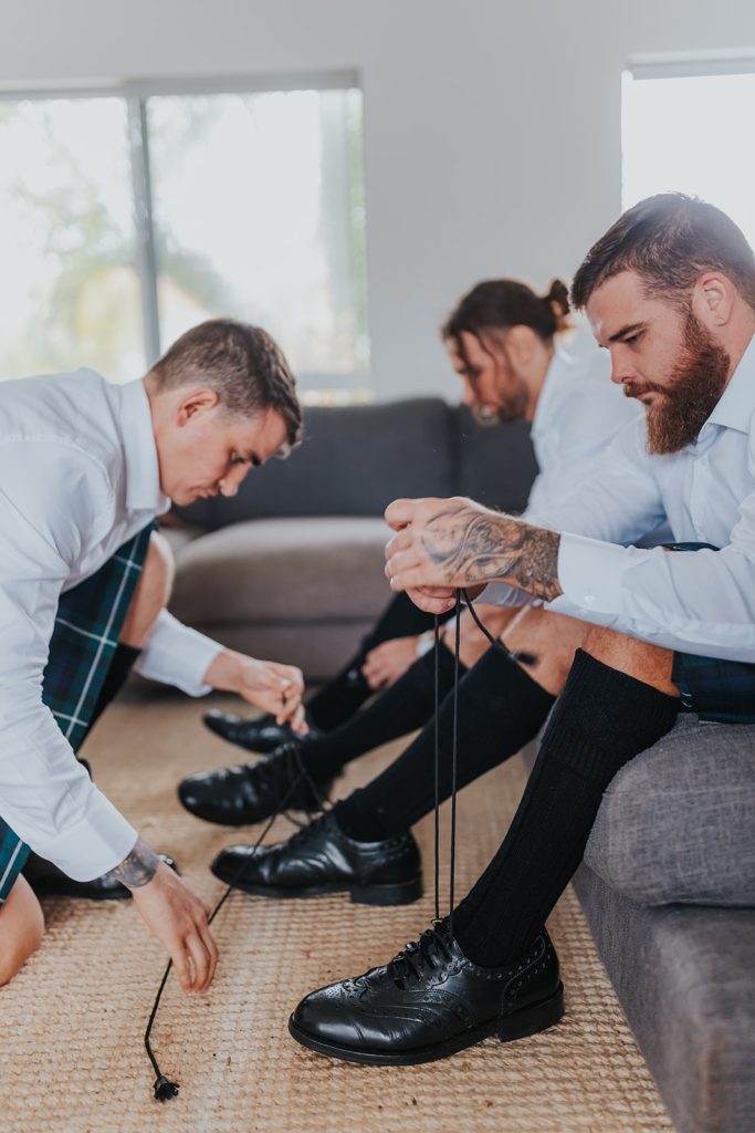 groom and groomsmen getting ready in kilts