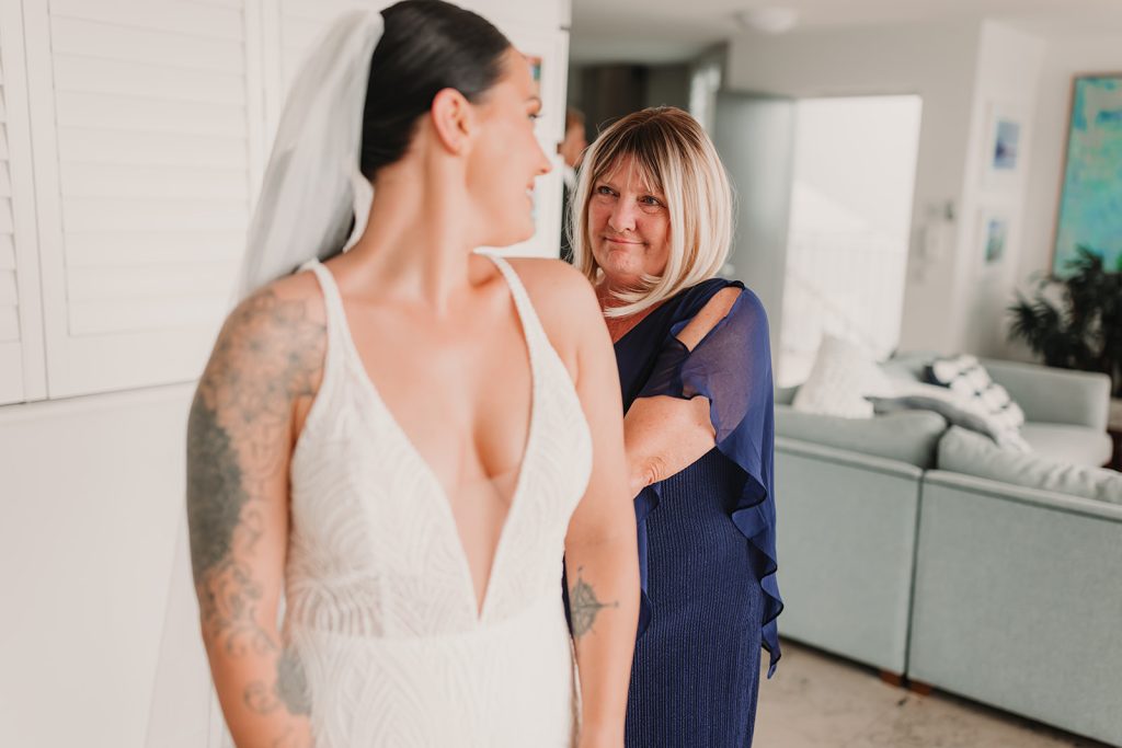 mother of the bride zipping her into dress on wedding day